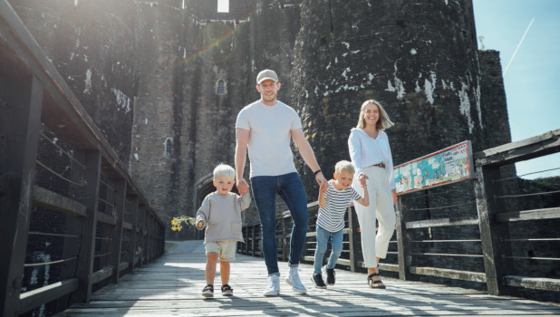 A family of four with two toddlers on a sunny day walking around Caerphilly Castle