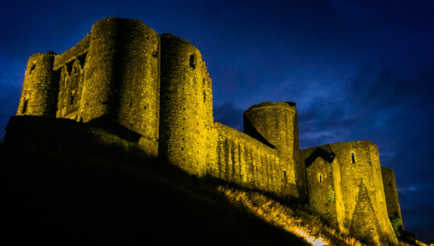 A prospective via of an illuminated Kidwelly castle at night